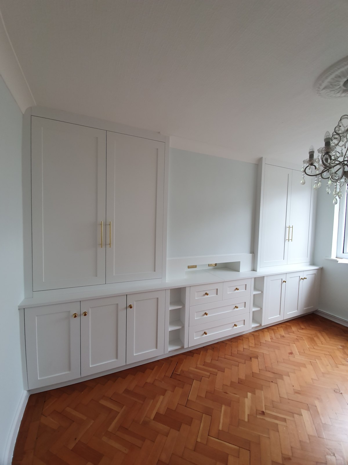 Fitted bedroom units with cupboards, drawers and brass handles