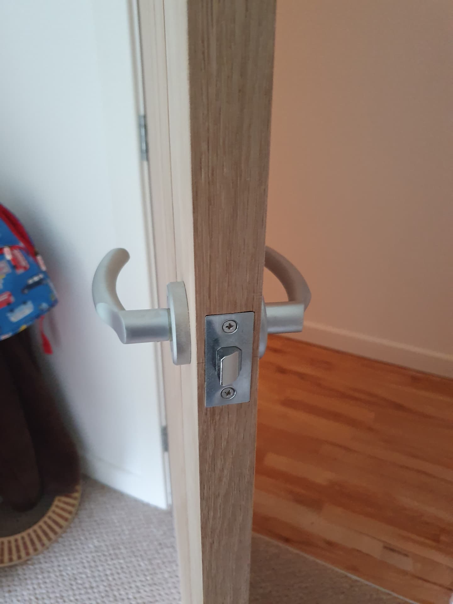 Detail of a flush-mounted latch plate and lever handle on a new door