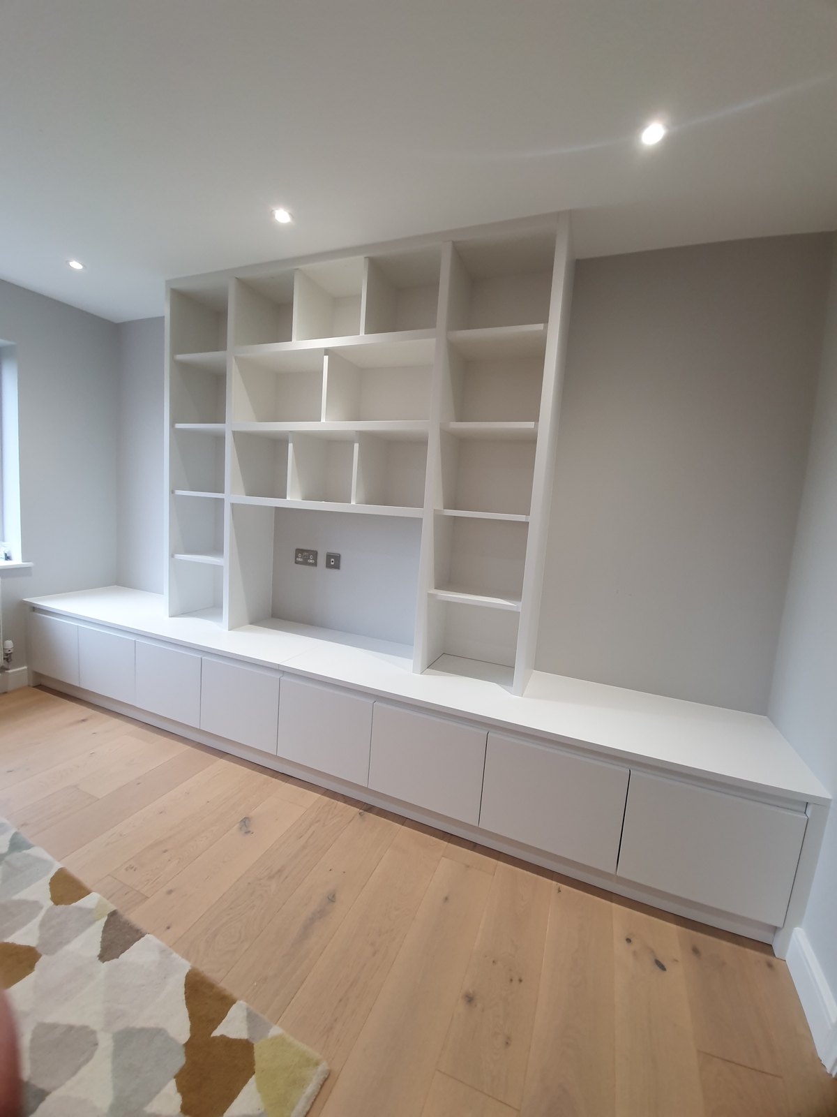 Long run of built-in shelving above low cupboards in a living room