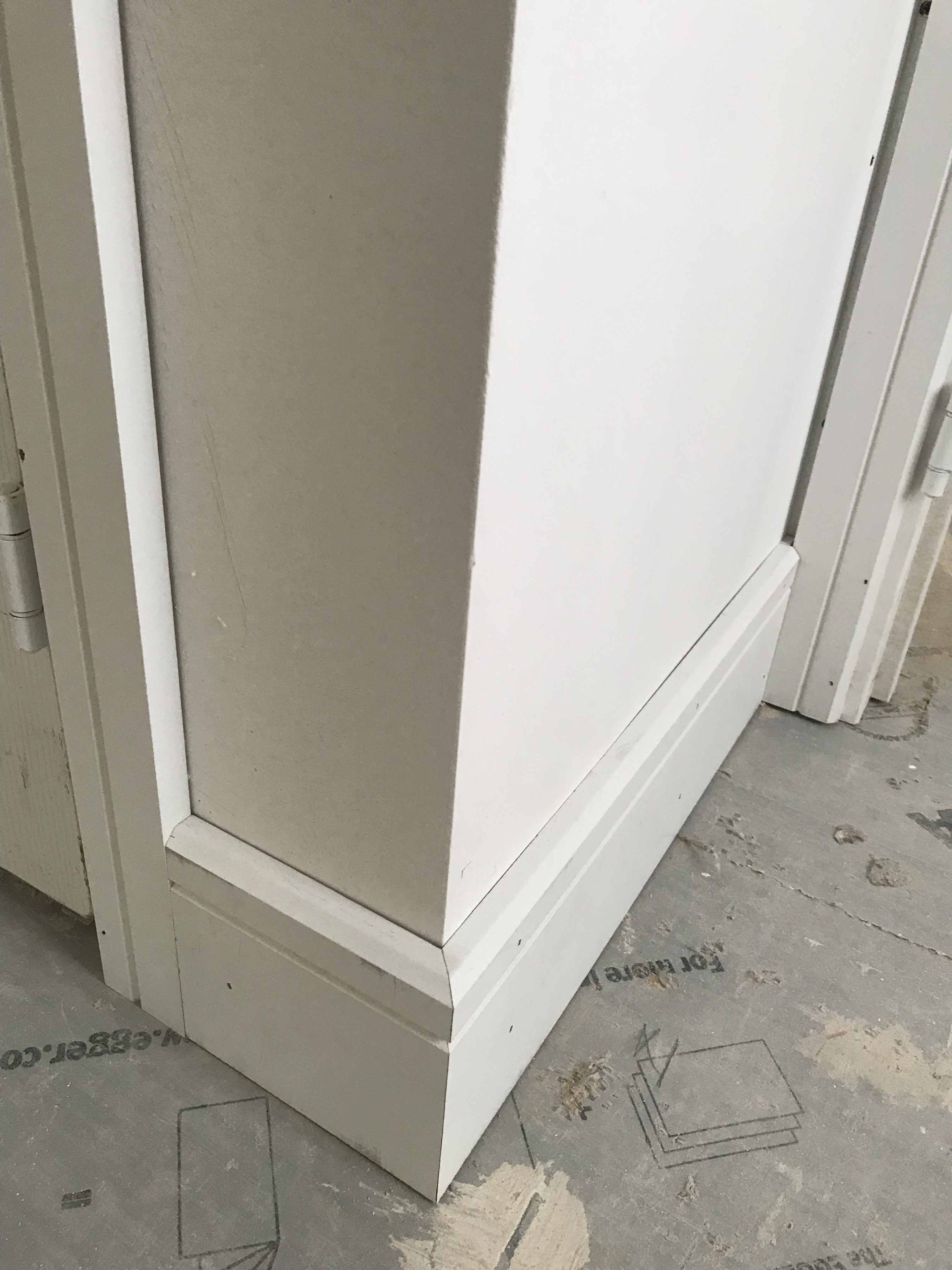 Mitered skirting board and architrave meeting at an external corner