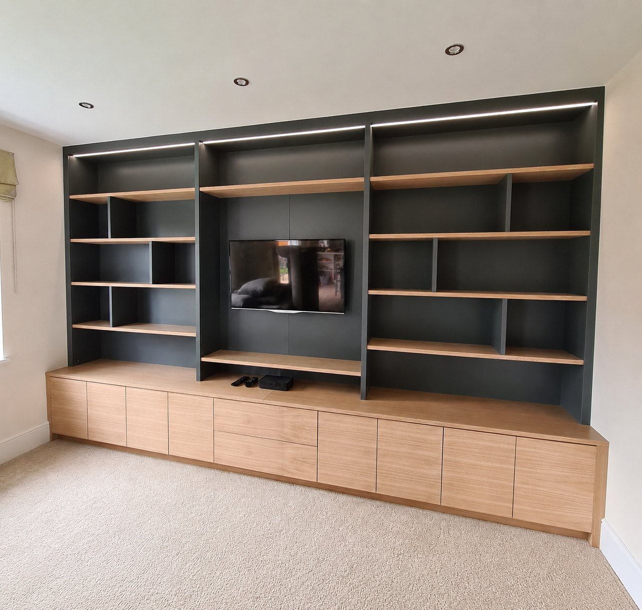 Charcoal and oak built-in media wall with open shelving and low drawer units
