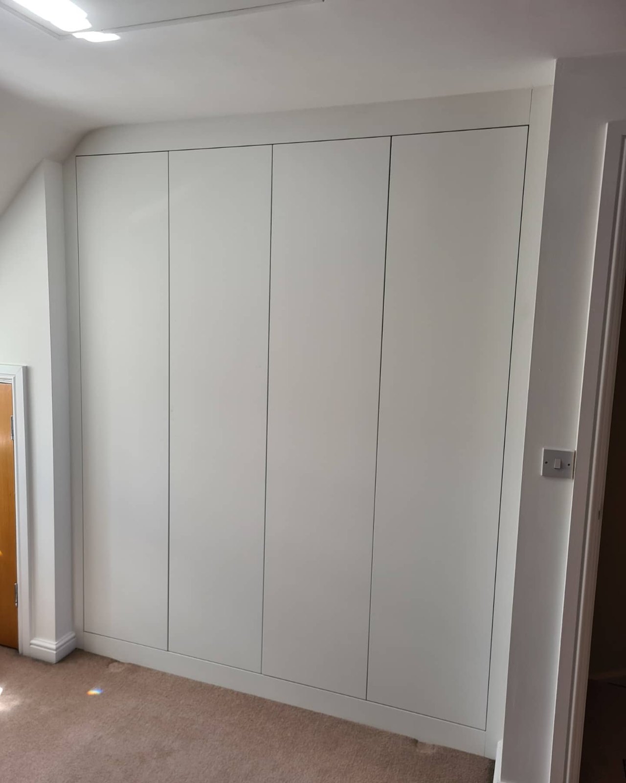 Floor-to-ceiling white fitted wardrobes scribed into an alcove