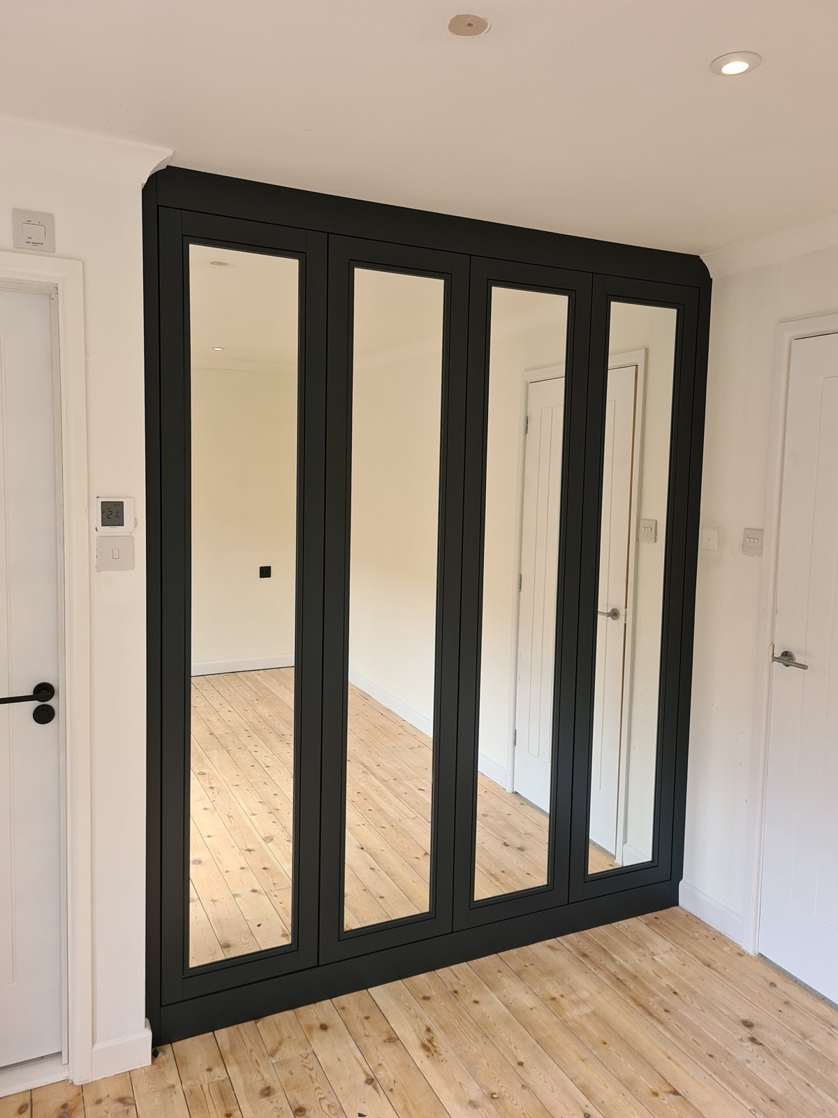 Mirrored wardrobe doors with dark painted frames in a bedroom