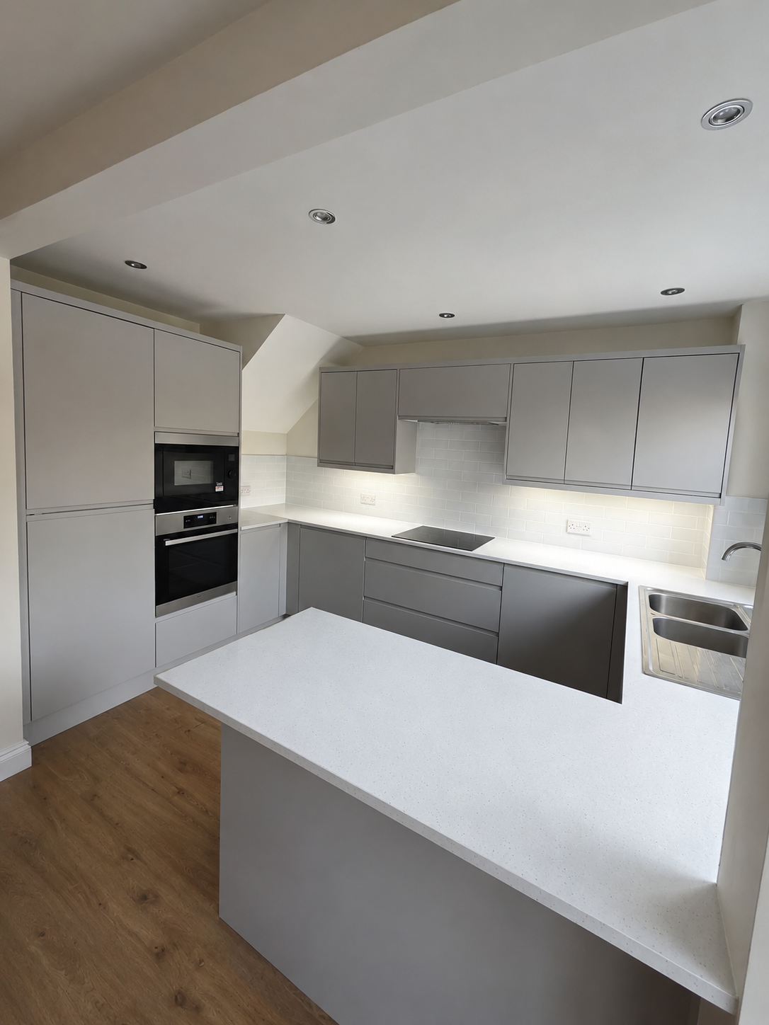 Modern handleless grey kitchen with peninsula and integrated appliances