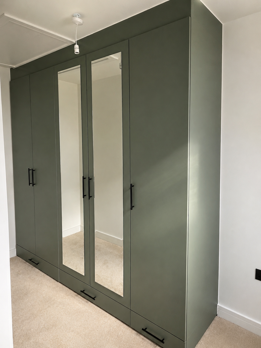 Wren sage green fitted wardrobes with mirrored centre doors and black bar handles