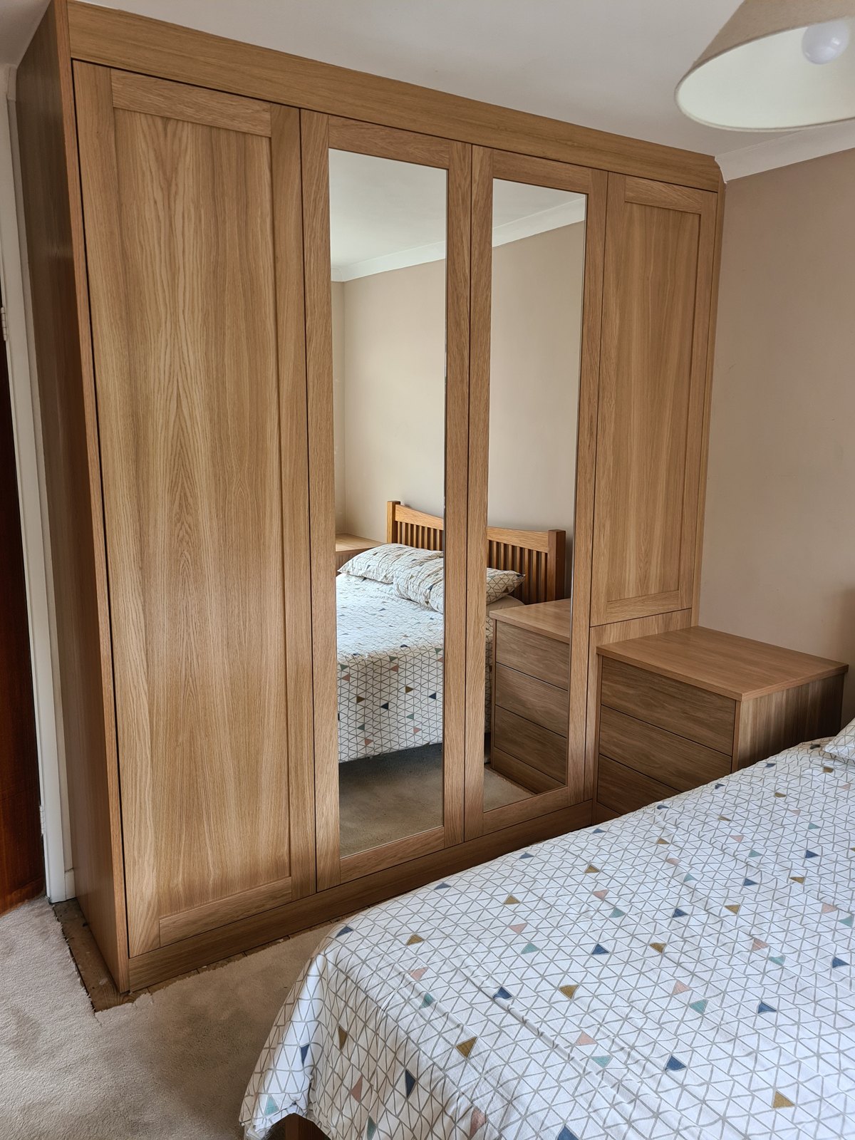Oak-finish wardrobes with mirrored centre doors and a matching bedside shelf