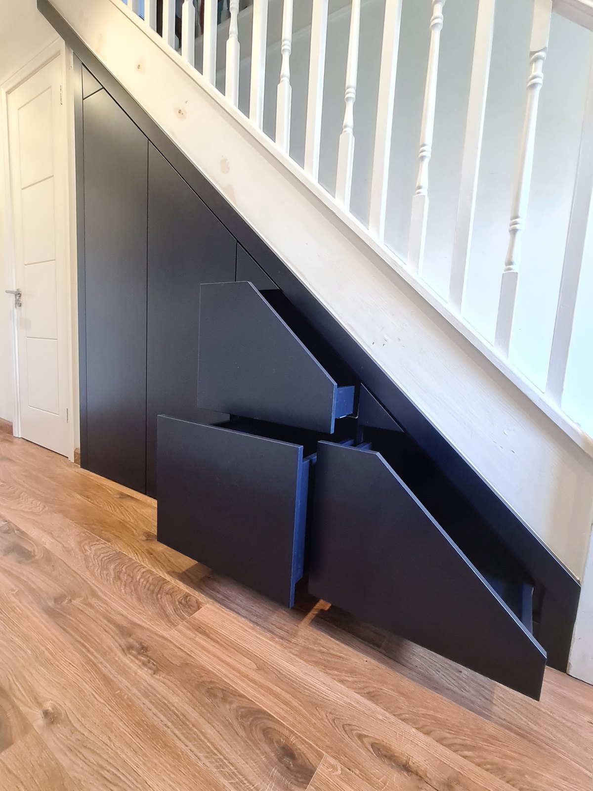 Deep pull-out drawers built into the space under a staircase