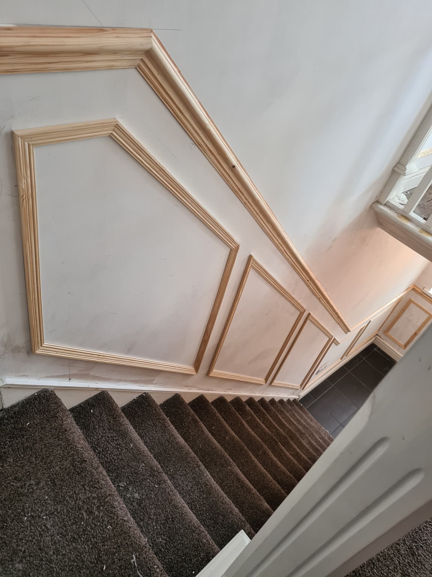 Geometric wall panelling cut to follow the angle of a staircase